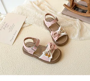 Detail view of pink and white girls' sandals with a bow, buckle, and non-slip rubber sole