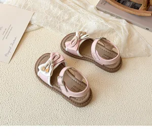 Detail of pink and white girls' sandals with bow decoration and adjustable metal buckle