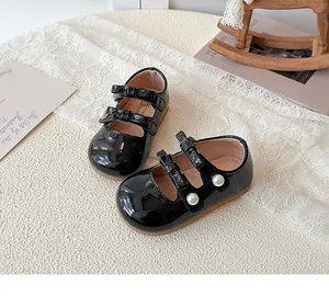 Détail de chaussures Mary Jane noires en cuir verni pour filles avec perles et nœuds
