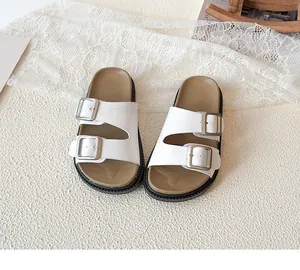 Detail view of white double-strap slides with silver metal buckles and non-slip sole