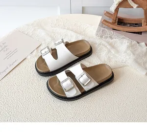 Detailed view of white double-strap leather sandals with silver buckles and ergonomic soles