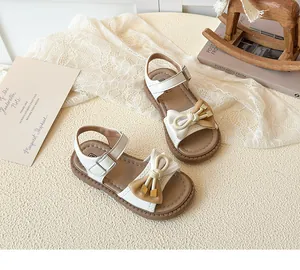 Close-up of color-block bow with gold hardware on girls' beige faux leather sandals