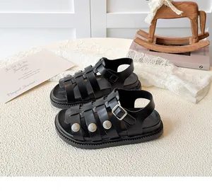 Detail of black gladiator sandals featuring silver relief rivets and adjustable buckles