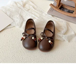 Close-up of deep brown Mary Jane shoes with bow decoration and beaded charms for girls