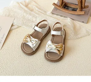 Detailed view of kids' bow sandals featuring white and tan leather with velcro ankle strap