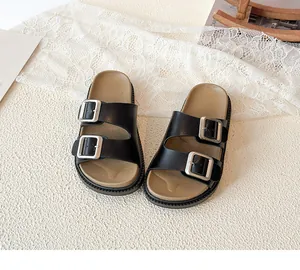 Detail view of children's black double-buckle sandals with ergonomic brown footbed