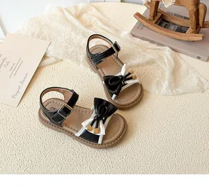 Detail of girls' sandals featuring black and white leather with a stylish double bow