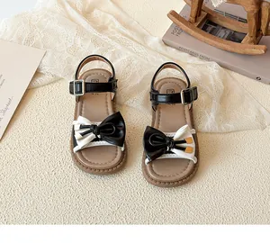 Detail of baby girl sandals featuring a bicolor bow and adjustable silver buckle
