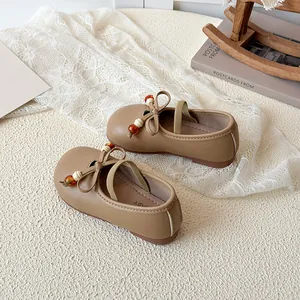 Brown girls Mary Jane shoes with decorative bow and beaded details in a cozy setting