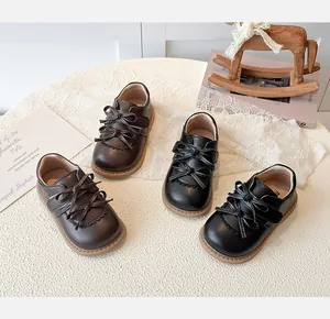 Chaussures classiques en cuir pour filles avec double nœud et velcro en noir et marron.
