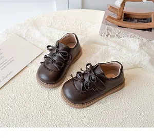 Détail de chaussures marron pour filles avec doubles nœuds et bords festonnés