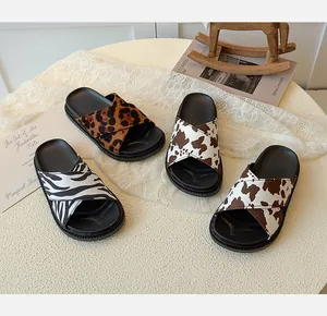 Close-up of kids' leopard and zebra print slides with soft soles and criss-cross straps