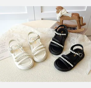 Dettaglio di sandali con perle per bambine in bianco e nero con suole antiscivolo