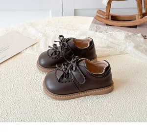 Détail de chaussures filles marron foncé avec double nœud et bords festonnés