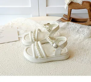 Dettaglio di sandali beige da bambina con decorazioni di perle e cinturino regolabile