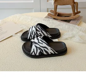 Detail of zebra print cross strap sandals with thick rubber sole on a stylish table