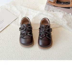 Détail de chaussures en cuir marron pour filles avec doubles nœuds et motifs ajourés