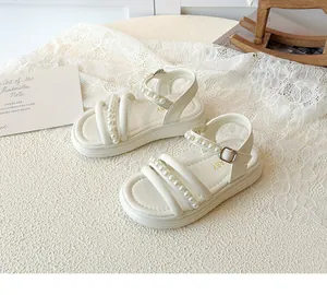 Dettaglio di sandali da bambina color crema con perle e cinturini incrociati e suola morbida