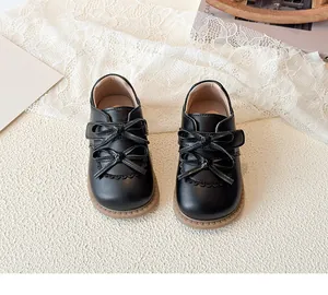 Détail de chaussures noires pour filles avec double nœud et bords découpés