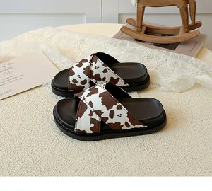 Detail of children's thick-soled slide with brown cow print on criss-cross straps