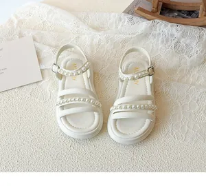 Dettaglio macro di sandali estivi da bambina bianco crema con eleganti decori di perle