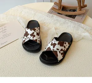 Detail of cross-strap kids slippers with cow print pattern and thick non-slip rubber soles