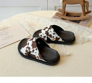 Close-up of kids' platform sandals featuring cow print crisscross straps and anti-slip sole