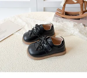 Détail de chaussures en cuir noir pour filles avec double nœud et bordure découpée