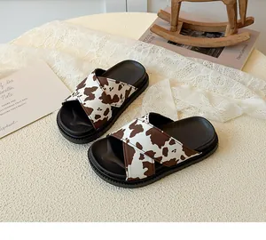 Detail of cow print cross-strap slippers with platform non-slip soles on a decorative surface