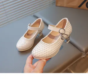 Detail von perlmuttweißen Mädchen-Mary-Janes mit Strasssteinen, Mondanhänger und Blockabsatz