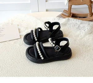 Dettaglio di sandali neri per bambina con eleganti cinturini di perle e fibbia in metallo