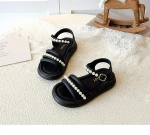 Dettaglio di sandali neri da bambina con perle su sfondo di pizzo e cavallo di legno