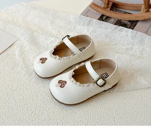 Detail von Kinder-Mary-Janes mit Spitzenbesatz und Pilzbestickung in Cremeweiß