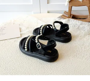 Dettaglio di sandali neri per bambini con perle bianche e soletta con logo dorato