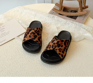 Detail of leopard print cross-strap kids' sandals on a white lace fabric background
