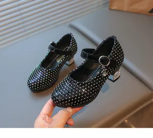 Detail von schwarzen Mädchen-Stöckelschuhen mit Strass, Steppmuster und Katzenanhänger