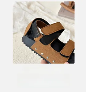 Detail of children's brown sandals with adjustable velcro straps and silver metal rivets