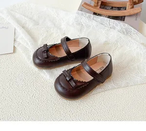 Detail von dunkelbraunen Baby-Mary-Janes mit Schleife und gewellten Saumverzierungen