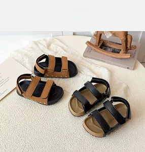 Detail view of children's sandals featuring velcro straps and decorative metal rivets