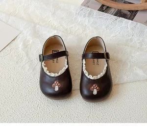 Detail der Pilzbestickung auf dunkelbraunen Mary-Jane-Lederschuhen mit weißer Spitze