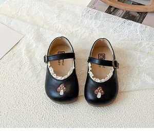 Detail von Mädchen Mary Janes in Schwarz mit weißem Spitzenbesatz und Pilzstickerei