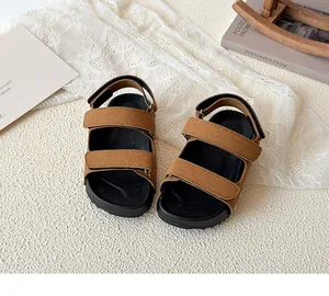 Close-up of children's brown suede sandals with double hook-and-loop strap detail