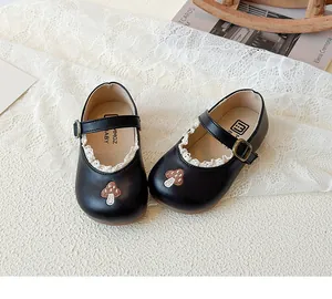 Detail von Baby Mary Jane Schuhen mit Pilzstickerei und zartem weißen Spitzenbesatz