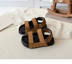Close-up of kids brown suede sandals featuring silver studs and velcro straps