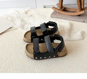 Close-up of black leather texture with velcro straps and silver stud details on kids' sandals