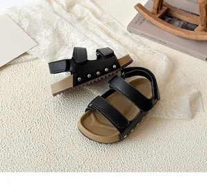 Detail of kids black sandals with velcro straps and silver stud accents on the sole