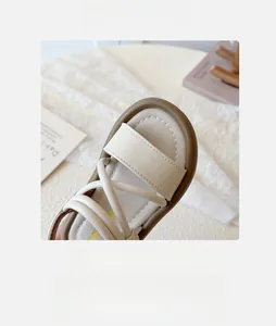 Detailed close-up of girls beige leather sandals with wide round toe and cross straps