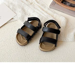 Detail of children's black sandals showing velcro straps and non-slip rubber soles