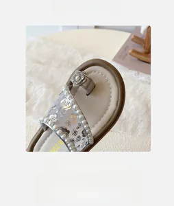 Détail de sandales pour filles avec accents floraux en strass et bordure en perles