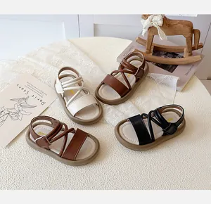 Flat lay of open-toe children's sandals in four colors with velcro straps on a table
